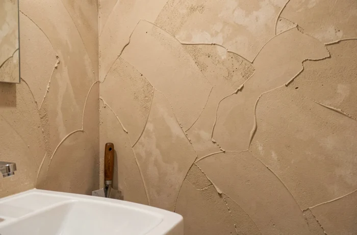 Mur de salle de bain recouvert d'un enduit décoratif à la chaux beige argile avec des traces de truelle organiques